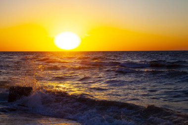 Günbatımı güzel denizde. Sprey ve taş sarı güneşin arka planı. Deniz manzarası.
