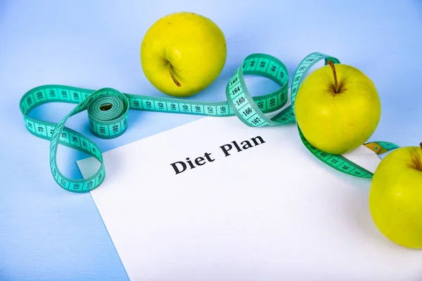 Apples, diet plan,dumbbells and measuring tape on a wooden background. Concept of diet and healthy lifestyle.