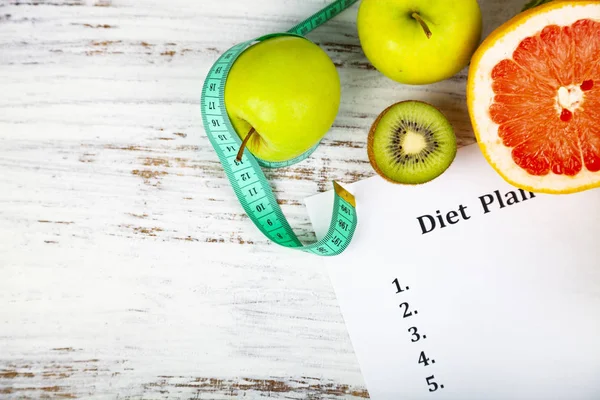Food and sheet of paper with a diet plan on a wooden background. Concept of diet and healthy lifestyle.