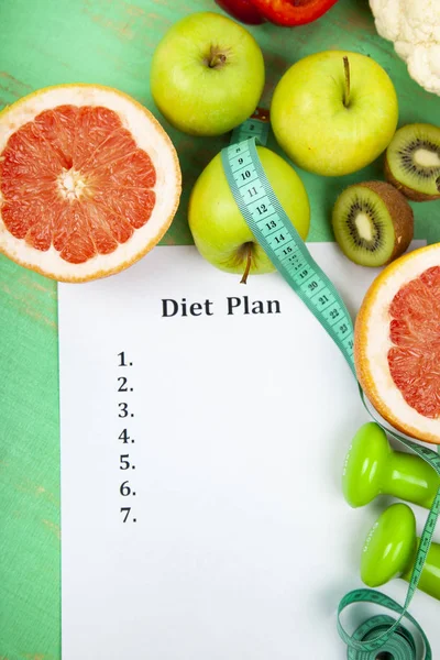 Food and sheet of paper with a diet plan on a green wooden background. Concept of diet and healthy lifestyle.