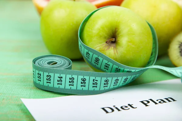 Food and sheet of paper with a diet plan on a green wooden background. Concept of diet and healthy lifestyle.