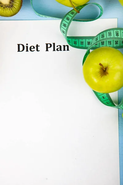 Food and sheet of paper with a diet plan on a blue wooden background. Concept of diet and healthy lifestyle.