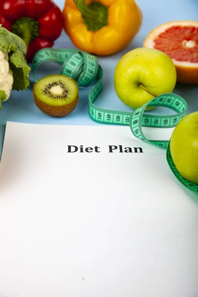 Food and sheet of paper with a diet plan on a blue wooden background. Concept of diet and healthy lifestyle.