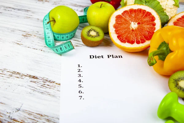 Food and sheet of paper with a diet plan on a wooden background. Concept of diet and healthy lifestyle.