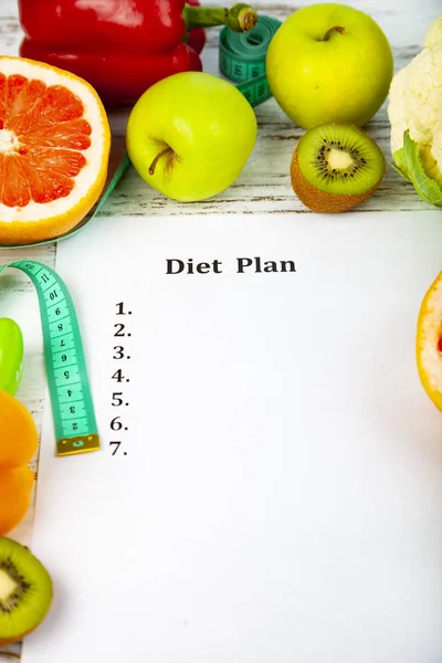 Food and sheet of paper with a diet plan on a wooden background. Concept of diet and healthy lifestyle.