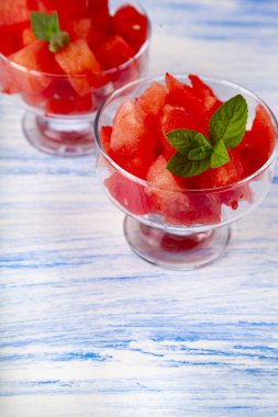 Karpuz ve nane bir plaka üzerinde mavi bir ahşap masa parçalar. Lezzetli tatlı.