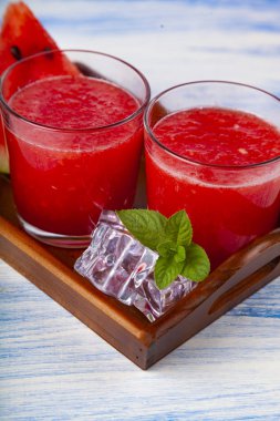 Karpuz ve nane bir tepsi üzerinde mavi bir ahşap masa üzerinde parçalar. Lezzetli tatlı.