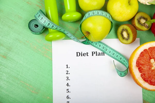 Food and sheet of paper with a diet plan on a green wooden background. Concept of diet and healthy lifestyle.