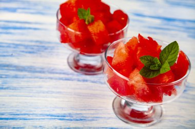 Karpuz ve nane bir plaka üzerinde mavi bir ahşap masa parçalar. Lezzetli tatlı.