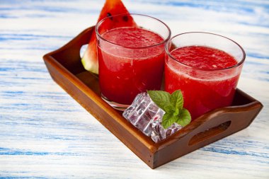 Karpuz suyu ve nane bir tepsi üzerinde mavi ahşap bir masa. Lezzetli tatlı.