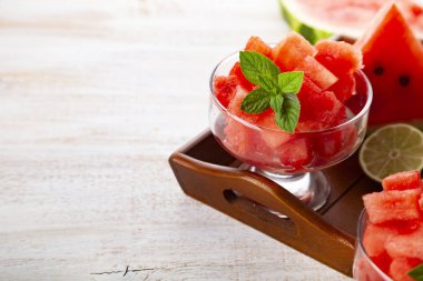 Karpuz ve nane bir ahşap tepsi üzerinde beyaz bir tablo üzerinde parçalar. Lezzetli tatlı.