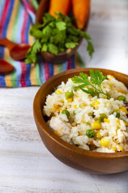 Masanın üzerinde bir ahşap kase sebze ile haşlanmış pirinç. Lezzetli vejetaryen yemek.