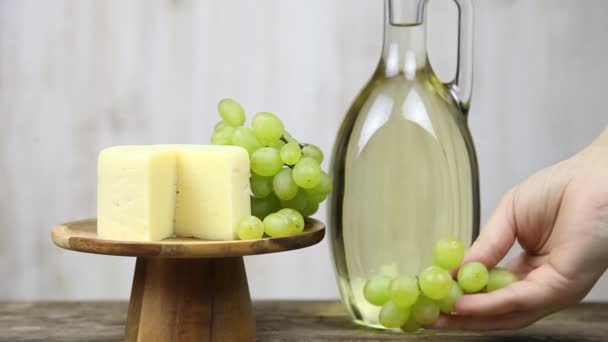 ブドウとチーズの背景にワインのグラスと女性の手 女性ニルス ワインを飲むと — ストック動画