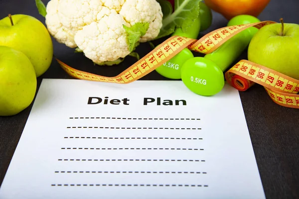 Food and sheet of paper with a diet plan on a green wooden background. Concept of diet and healthy lifestyle.