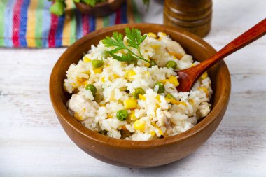 Masanın üzerinde bir ahşap kase sebze ile haşlanmış pirinç. Lezzetli vejetaryen yemek.