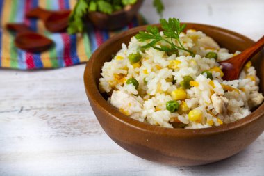 Masanın üzerinde bir ahşap kase sebze ile haşlanmış pirinç. Lezzetli vejetaryen yemek.