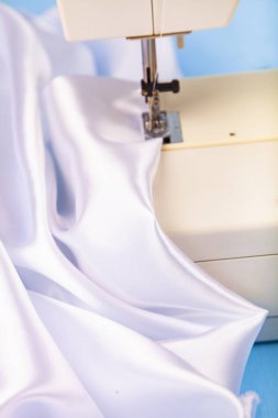 Dikiş makinesi ve beyaz saten kumaş yakın çekim