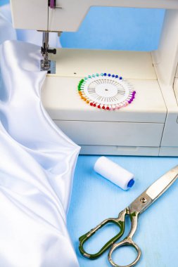 Dikiş makinesi ve beyaz saten kumaş yakın çekim