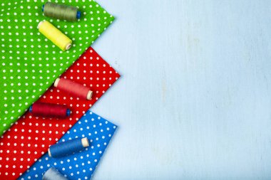 Dikiş aksesuarları, mavi ahşap arka plan üzerinde çok renkli kumaşlar. Kumaş ve iplik.