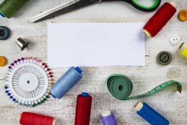 Dikiş aksesuarları ve kağıt ahşap arka plan üzerinde. Teyp, iğne, düğme, fermuar, makas ve iş parçacığı ölçme.