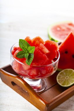 Karpuz ve nane bir ahşap tepsi üzerinde beyaz bir tablo üzerinde parçalar. Lezzetli tatlı.