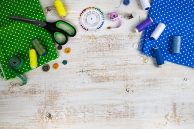 Dikiş aksesuarları ve kumaş bir ahşap zemin üzerinde. Kumaşlar, teyp, iğne, düğmeler ve iş parçacığı ölçme.