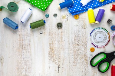 Dikiş aksesuarları ve kumaş bir ahşap zemin üzerinde. Kumaşlar, teyp, iğne, düğmeler ve iş parçacığı ölçme.