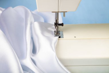 Dikiş makinesi ve beyaz saten kumaş yakın çekim