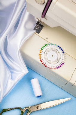 Dikiş makinesi ve beyaz saten kumaş yakın çekim