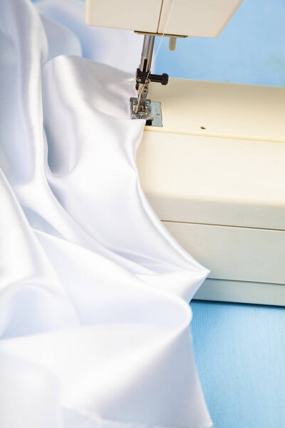 Sewing machine and white satin fabric close-up