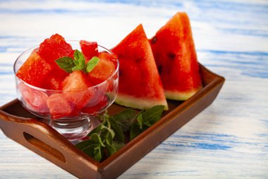 Karpuz ve nane bir ahşap tepsi üzerinde beyaz bir tablo üzerinde parçalar. Lezzetli tatlı.