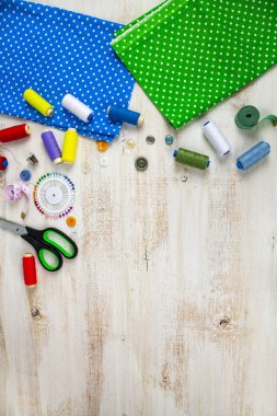 Dikiş aksesuarları ve kumaş bir ahşap zemin üzerinde. İplik ve kumaş metin için yer ile sınır.