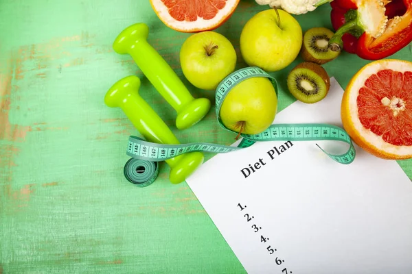 Food and sheet of paper with a diet plan on a green wooden background. Concept of diet and healthy lifestyle.