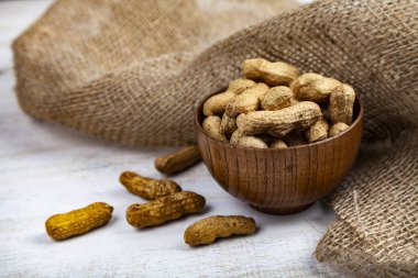 Fıstık bir ahşap kase ve masanın üzerine çuval bezi. Lezzetli ve sağlıklı fındık. 