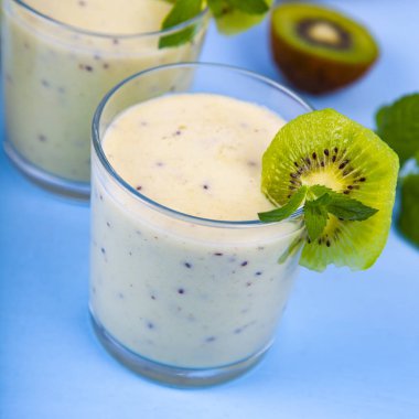 Bir muz ve mavi ahşap bir masa üzerinde kivi smoothies. Lezzetli tatlı.
