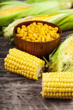 Ham Mısır ve eski bir ahşap masa üzerinde bir kase konserve mısır.