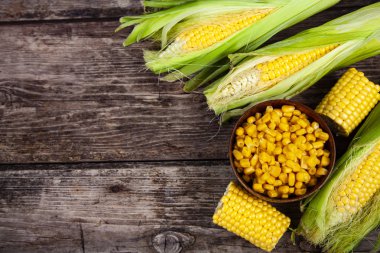 Ham Mısır ve eski bir ahşap masa üzerinde bir kase konserve mısır.