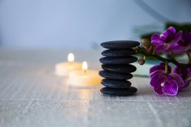 Spa uygulamaları ahşap masa üzerinde. Deniz tuzu, spa taşları, orkide ve yanan mumlar.