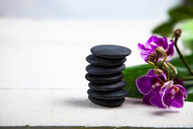 Spa uygulamaları ahşap masa üzerinde. Deniz tuzu, spa taşları, orkide ve yanan mumlar.