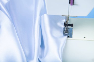 Dikiş makinesi ve beyaz saten kumaş yakın çekim