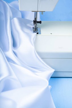 Dikiş makinesi ve beyaz saten kumaş yakın çekim