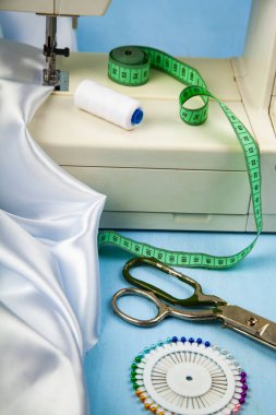 Dikiş makinesi ve beyaz saten kumaş yakın çekim
