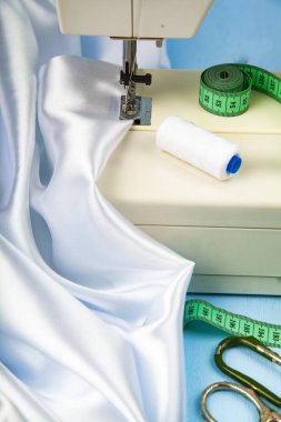 Dikiş makinesi ve beyaz saten kumaş yakın çekim