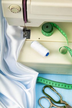 Dikiş makinesi ve beyaz saten kumaş yakın çekim