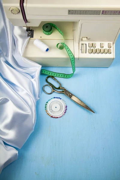 Dikiş makinesi ve beyaz saten kumaş yakın çekim
