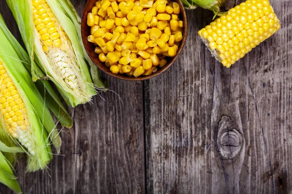 Olgun sarı Mısır ve ahşap bir masa üzerinde bir ahşap kase konserve mısır. Sarı olgun Mısır, üstten görünüm