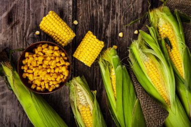 Olgun Mısır eski ahşap masa. Ham Mısır ve ahşap bir kase konserve mısır.