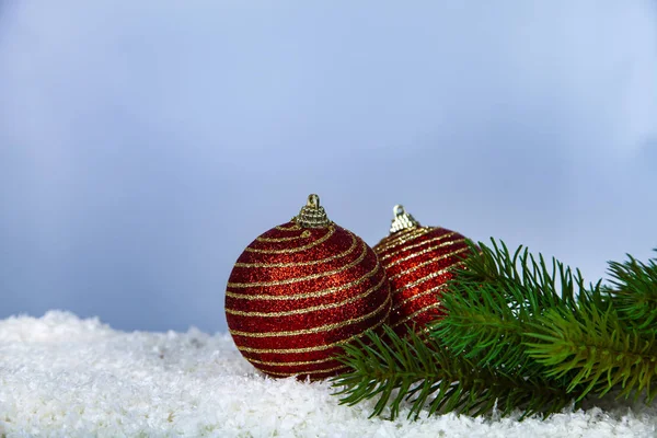 つの赤いクリスマス ボールと背景に雪の中でモミの枝 — ストック写真