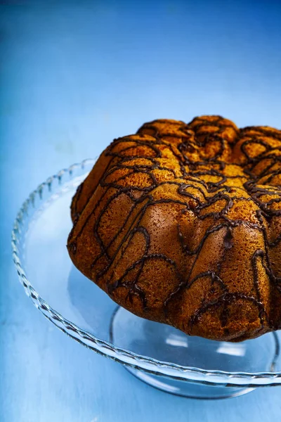 Heerlijke Chocolade Cake Een Transparante Schotel Een Blauwe Achtergrond — Stockfoto