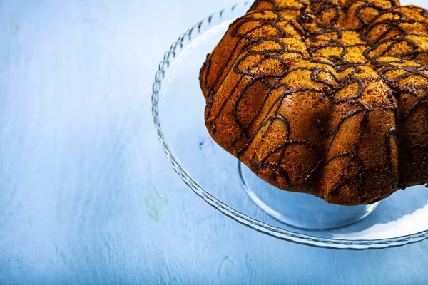 Heerlijke Chocolade Cake Een Transparante Schotel Een Blauwe Achtergrond — Stockfoto